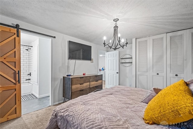 carpeted bedroom featuring a textured ceiling, a barn door, an inviting chandelier, connected bathroom, and a closet