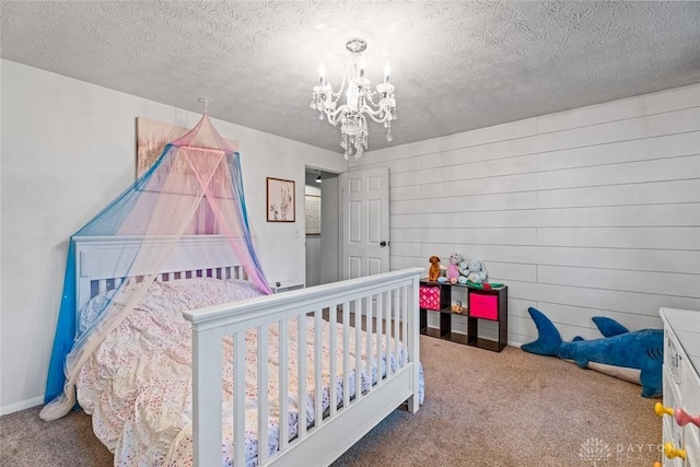 carpeted bedroom featuring a chandelier and a textured ceiling