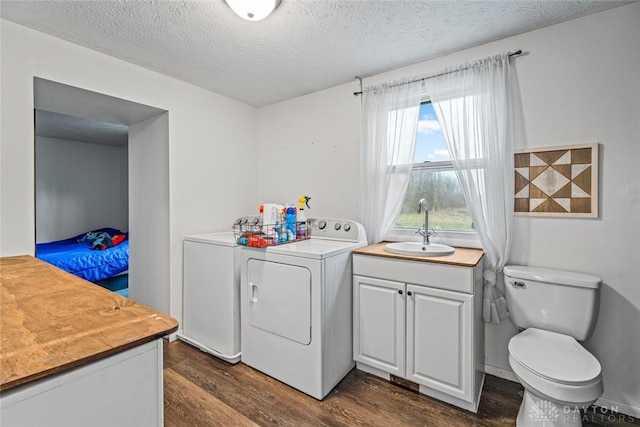 clothes washing area with separate washer and dryer, sink, dark wood-type flooring, and a textured ceiling