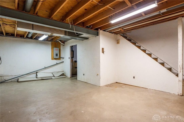 unfinished basement featuring electric panel and stairs