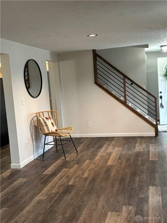 unfurnished room featuring dark wood-style floors, stairs, and baseboards