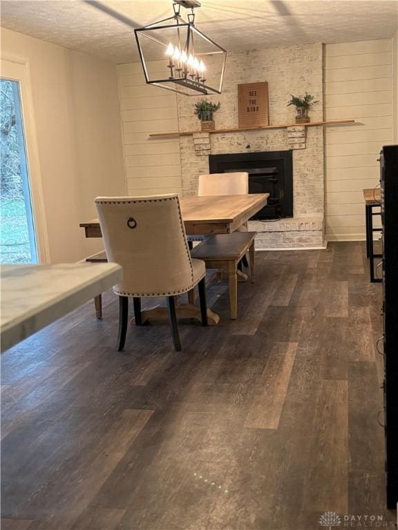 dining area with dark wood-style floors, wood walls, a textured ceiling, and a fireplace