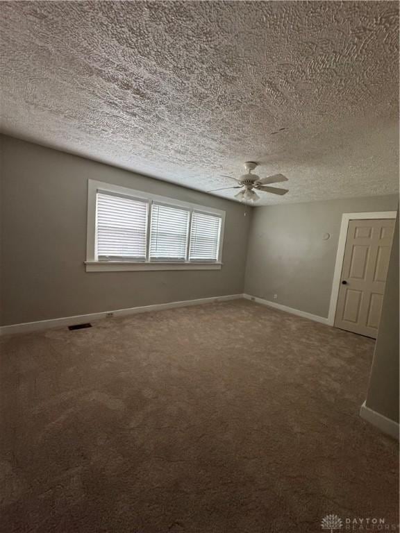 carpeted spare room with ceiling fan and a textured ceiling