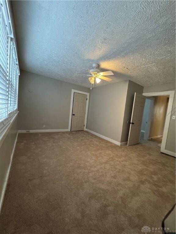 empty room with carpet flooring, ceiling fan, and a textured ceiling