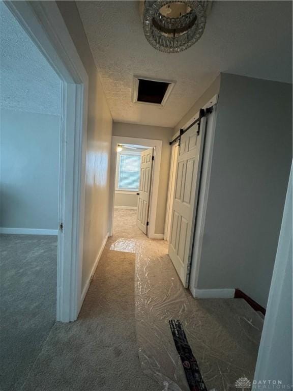 hallway featuring a barn door and a textured ceiling