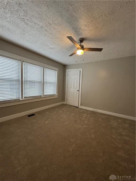 spare room featuring carpet, ceiling fan, and a textured ceiling