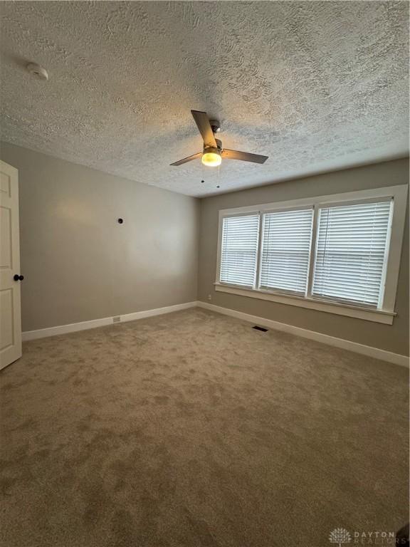 spare room with ceiling fan, carpet floors, and a textured ceiling