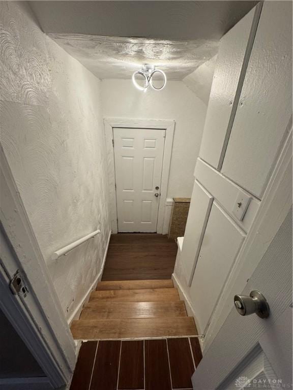 staircase with a textured ceiling and vaulted ceiling