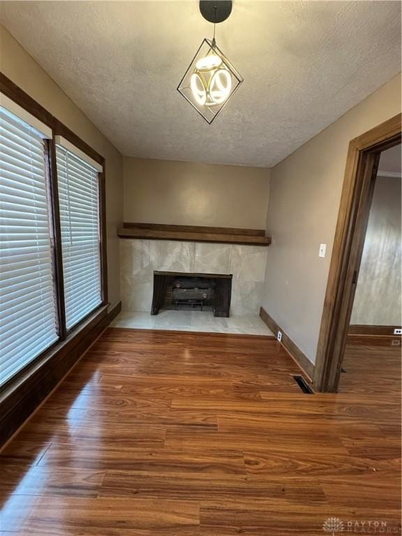 unfurnished living room featuring a fireplace, hardwood / wood-style floors, a healthy amount of sunlight, and a textured ceiling