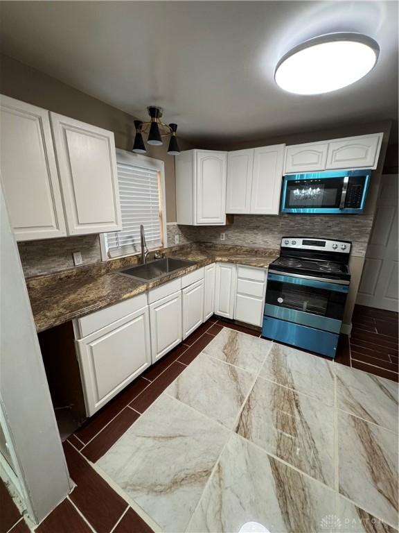 kitchen featuring decorative backsplash, stainless steel appliances, white cabinetry, and sink