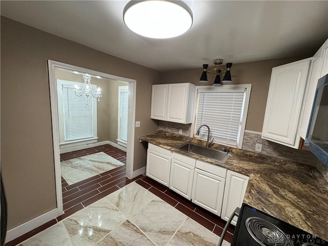 kitchen with an inviting chandelier, white cabinetry, sink, and range