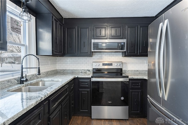 kitchen featuring appliances with stainless steel finishes, dark hardwood / wood-style flooring, light stone countertops, and sink