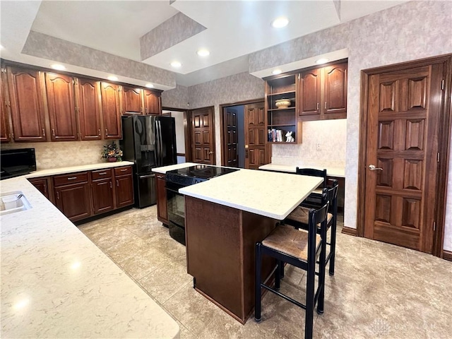 kitchen featuring a breakfast bar, a center island, and black appliances