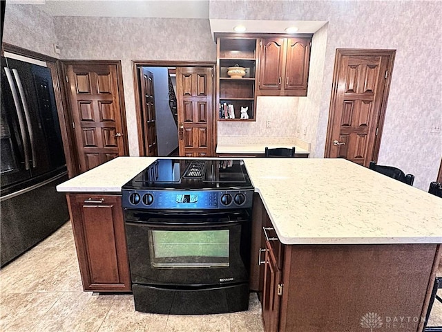 kitchen featuring dark brown cabinetry, a center island, light tile patterned flooring, and black appliances