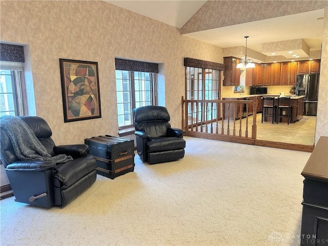 living room with light colored carpet, a healthy amount of sunlight, lofted ceiling, and a notable chandelier