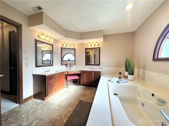 bathroom with a washtub and vanity