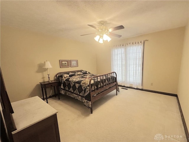 carpeted bedroom with ceiling fan and a textured ceiling