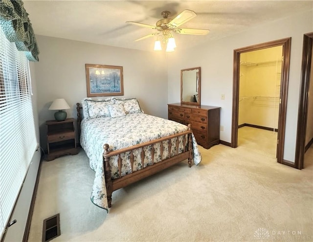 bedroom with ceiling fan, light colored carpet, a spacious closet, and a closet