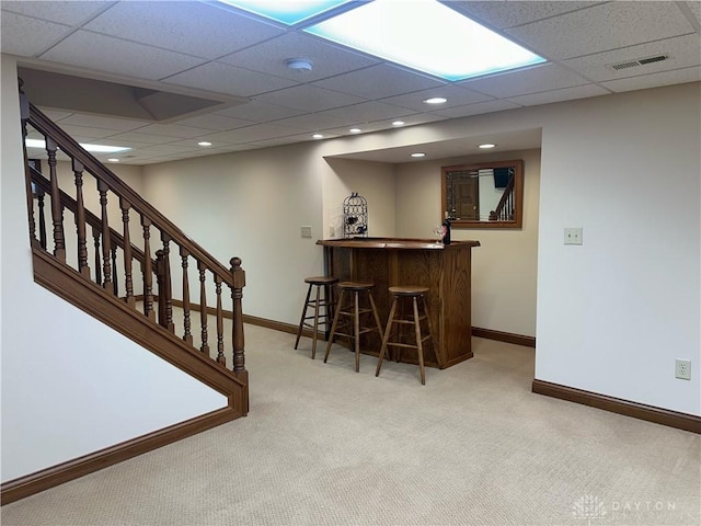 bar featuring a drop ceiling and light colored carpet