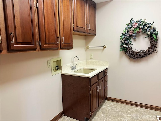 clothes washing area featuring cabinets, sink, and washer hookup