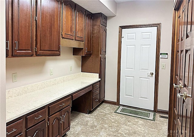 kitchen featuring dark brown cabinets and light stone counters