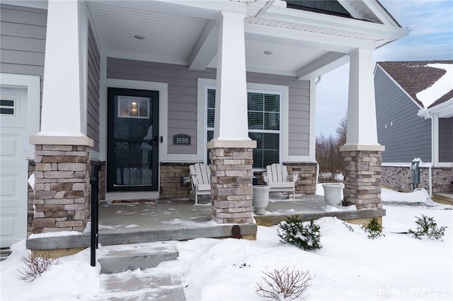 snow covered property entrance with covered porch