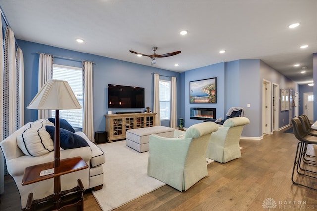 living room with ceiling fan, a healthy amount of sunlight, and light wood-type flooring