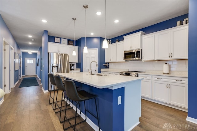 kitchen featuring a kitchen island with sink, sink, white cabinets, and appliances with stainless steel finishes