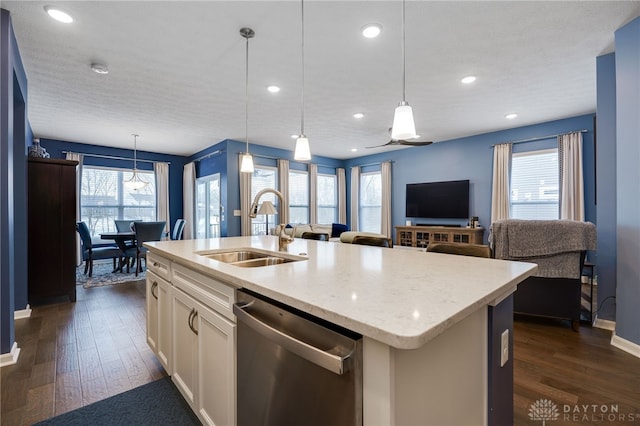 kitchen with sink, dark hardwood / wood-style flooring, stainless steel dishwasher, pendant lighting, and a kitchen island with sink