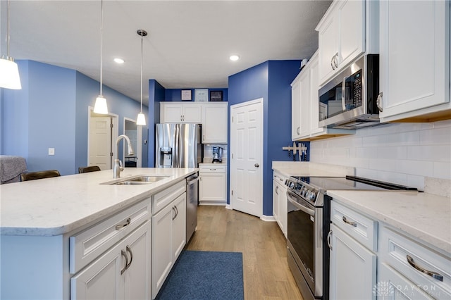 kitchen with pendant lighting, sink, appliances with stainless steel finishes, tasteful backsplash, and white cabinetry