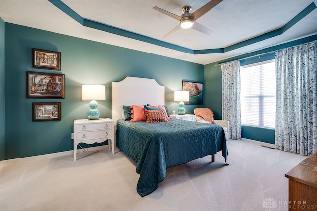 carpeted bedroom featuring a raised ceiling and ceiling fan