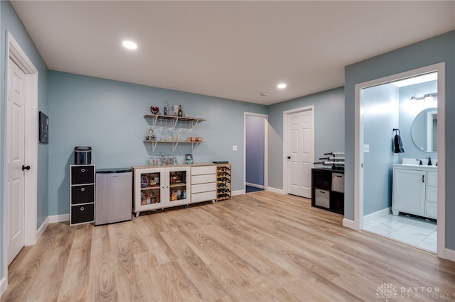 bar featuring sink, light hardwood / wood-style flooring, and fridge