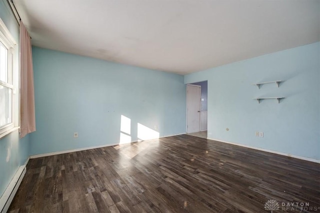 empty room with dark hardwood / wood-style flooring and a baseboard heating unit