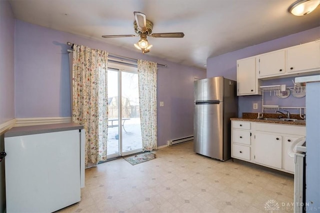 kitchen with sink, stainless steel refrigerator, a baseboard radiator, white cabinets, and stove