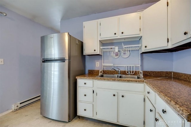 kitchen featuring sink, stainless steel refrigerator, white cabinets, and baseboard heating