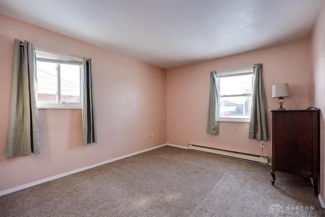 carpeted empty room featuring baseboard heating and plenty of natural light