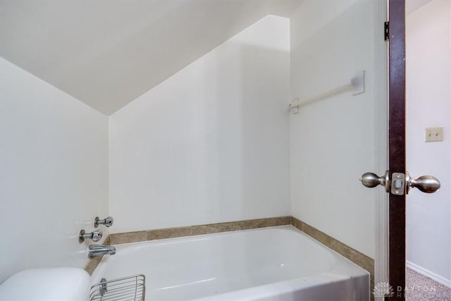 bathroom with vaulted ceiling and a bathtub