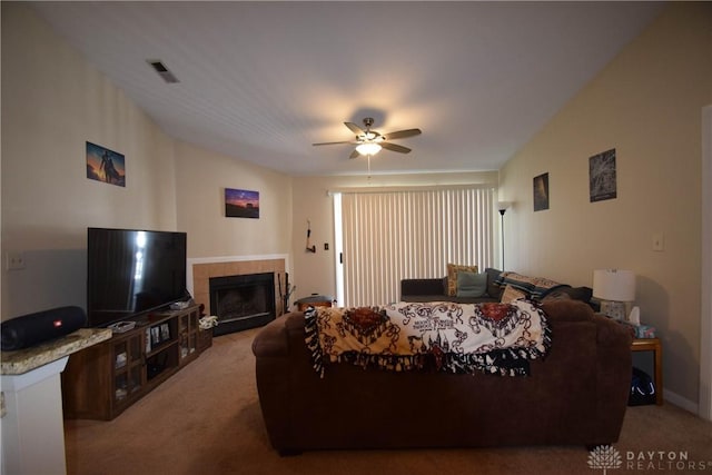 carpeted living room featuring a tiled fireplace and ceiling fan