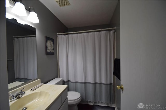 bathroom featuring walk in shower, vanity, and toilet