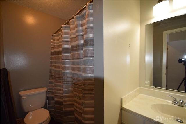 bathroom with vanity, curtained shower, a textured ceiling, and toilet