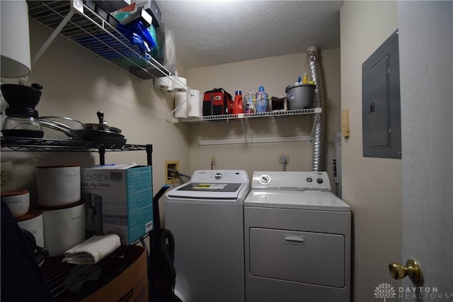 clothes washing area featuring electric panel, washer and clothes dryer, and a textured ceiling