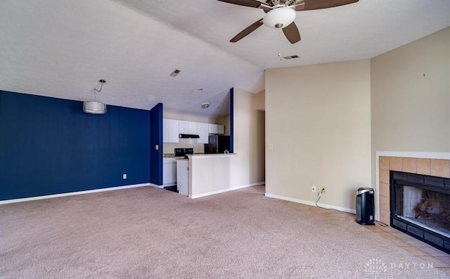 unfurnished living room with a tiled fireplace, lofted ceiling, and ceiling fan