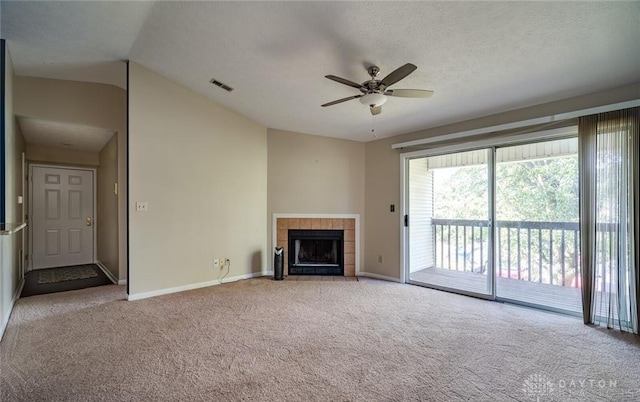 unfurnished living room featuring lofted ceiling, ceiling fan, a textured ceiling, a tiled fireplace, and light carpet