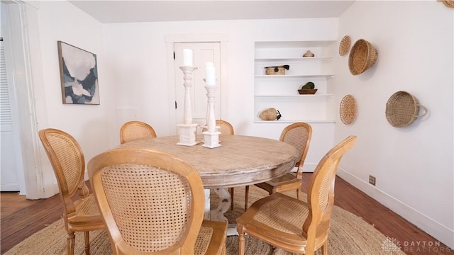 dining space with built in shelves and dark wood-type flooring