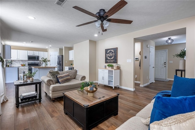 living room with hardwood / wood-style flooring, ceiling fan, and a textured ceiling