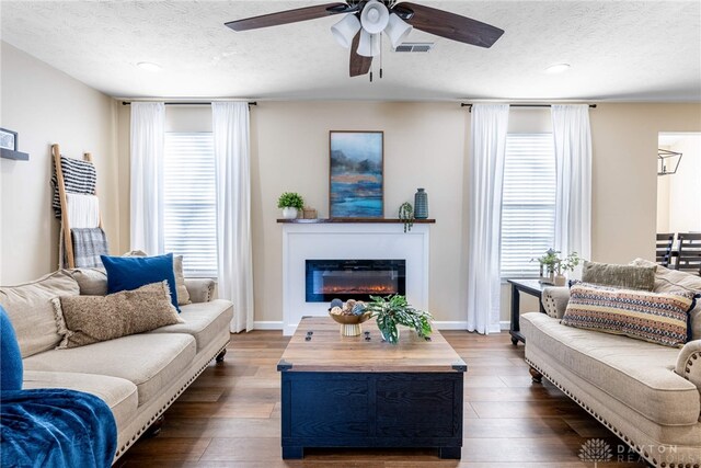 living room with dark hardwood / wood-style flooring, a textured ceiling, plenty of natural light, and ceiling fan