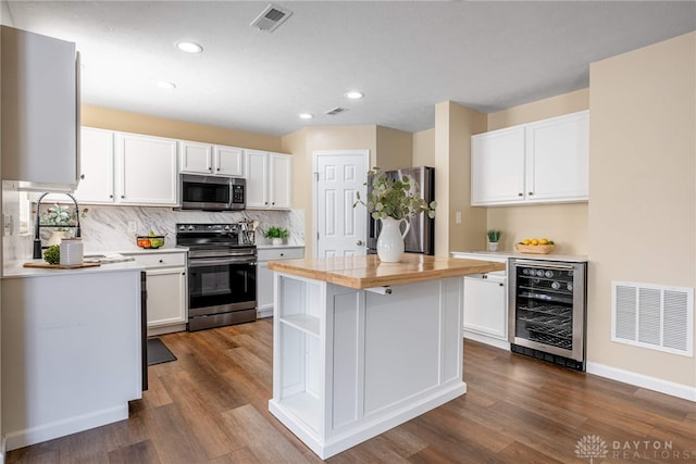 kitchen with appliances with stainless steel finishes, a center island, white cabinetry, and wine cooler