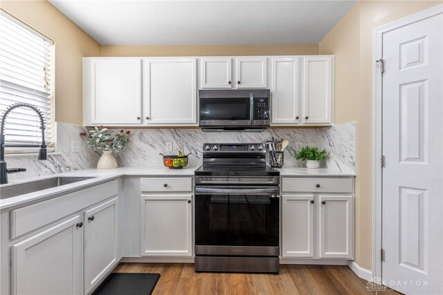 kitchen with decorative backsplash, stainless steel appliances, white cabinetry, and sink