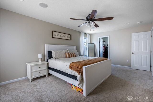 bedroom featuring ceiling fan, a spacious closet, light carpet, and a closet