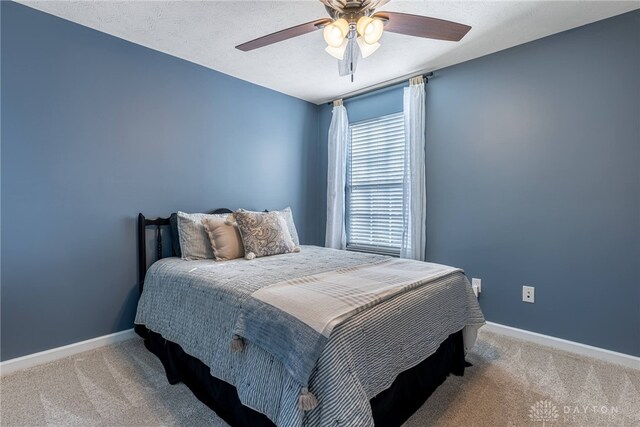 bedroom featuring ceiling fan, light carpet, and a textured ceiling